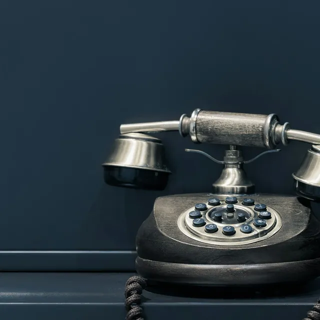 A rotary telephone on a dark desk — buys negotiated by phone